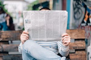 Fapadon ülő ember újságot olvas
